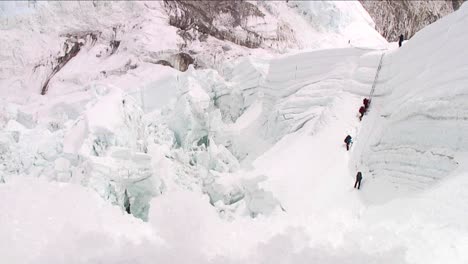 climbers on large ladder at top of icefall