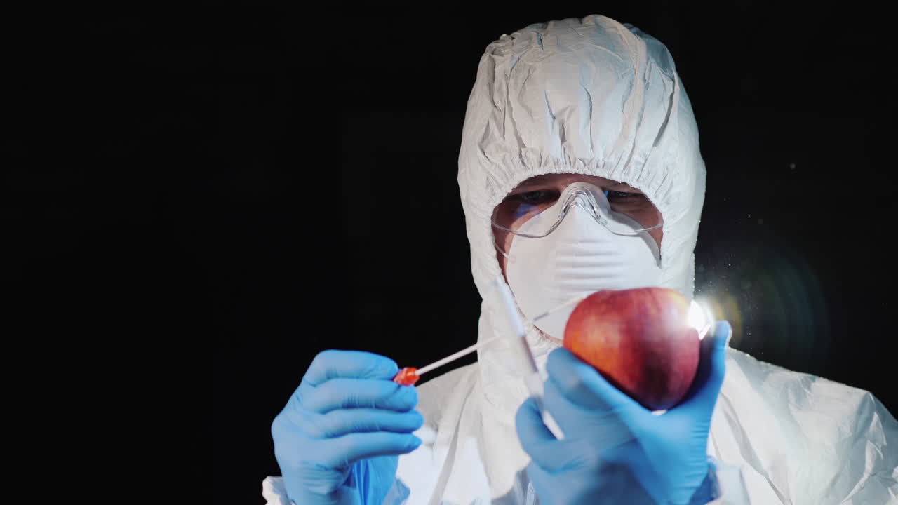 un hombre con ropa protectora y guantes toma un frotis de una manzana grande 2