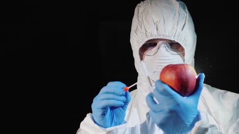 a man in protective clothing and gloves takes a smear from a large apple 2