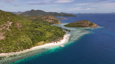 aerial footage of coron island, philippines, showcasing a seamless blend of sparkling waters and verdant tropical terrain. with a boat anchored in the water.
