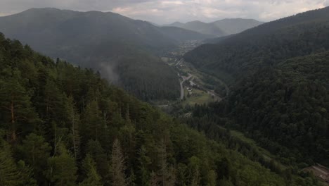 flying over treetops looking down into valley revealing a bend in a river and clusters of homes on the bank of the river