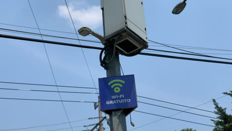 Señal-Wifi-Gratuita-En-Una-Farola-En-La-Ciudad-De-México-Con-Luz-De-Calle-Y-Cables-En-El-Fondo-Contra-El-Cielo-Azul