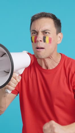 excited man with belgian flag on face using a megaphone
