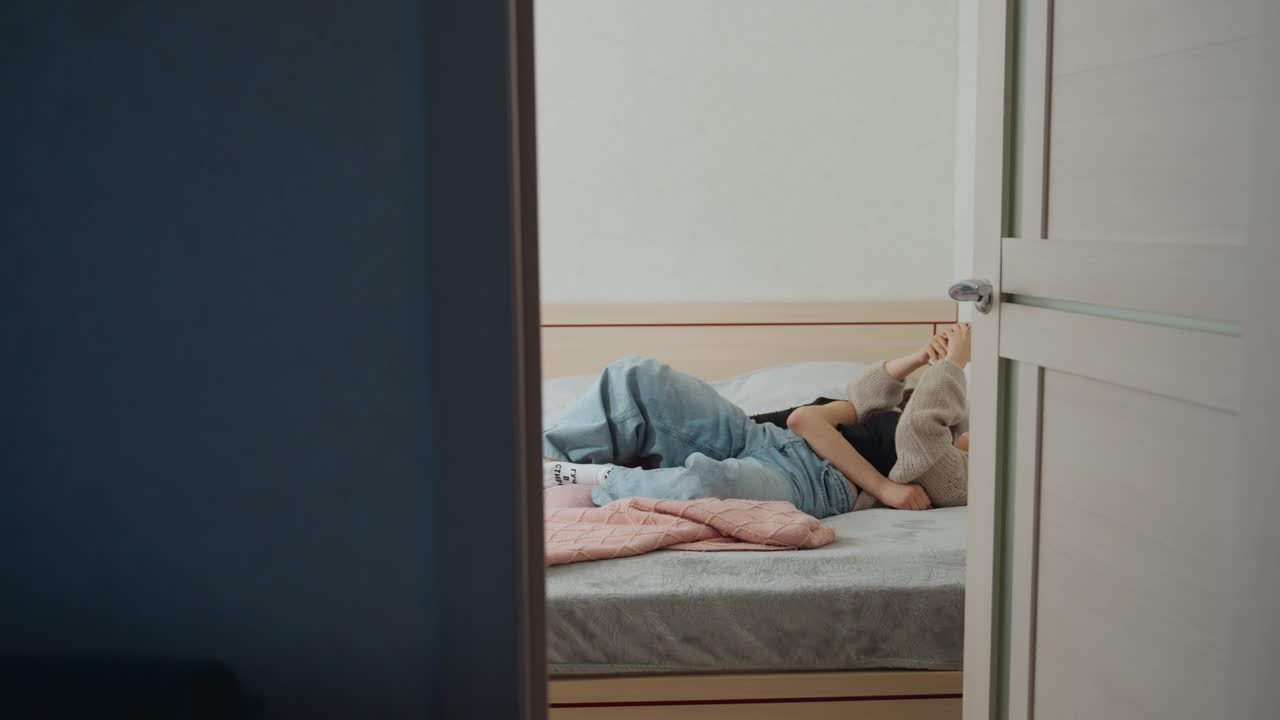 Woman Waking White Friend On Bed In Soft Morning Light, Tender Bedside Scene With Blankets And Pillows, Attentive Roommate Checking On Sleep And Offering Support, Calm Routine In Cozy Minimal Bedroom