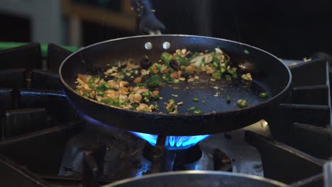 chef flambés vegetables in a hot pan