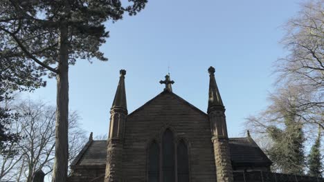 rural english woodland village church pull back aerial tilt down over graveyard foliage