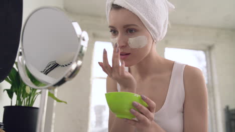 mujer aplicando mascarilla facial