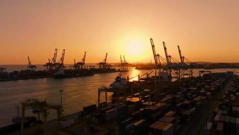watch as the sun sets behind a busy cargo port, illuminating cranes and container ships. the vibrant colors in the sky enhance the industrial landscape of shipping operations.