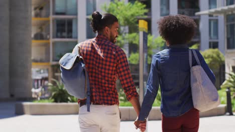 diverse couple walking on the street holding hands smiling and talking