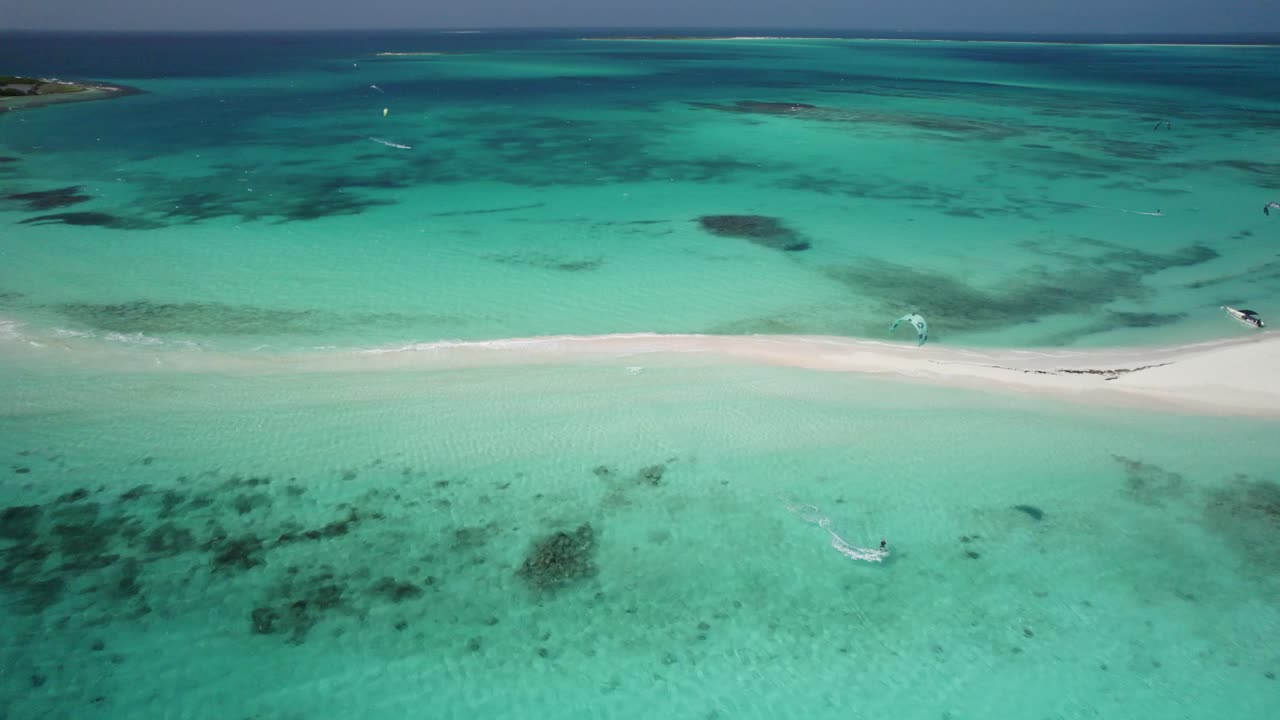 Aerial view of kitesurfers in turquoise water near a sandbar