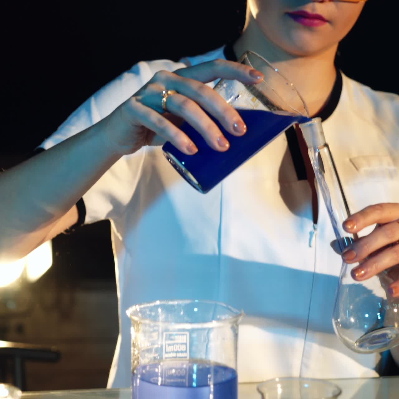 Woman scientist mixing together two liquid substances. Scientific discoveries. Experiments in the laboratory
