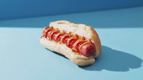 video of hot dog with mustard and ketchup on a blue surface