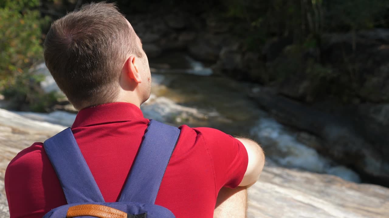 산 강 근처 에 앉아 있는 배 을 들고 있는 남성 여행자 의 근접 사진