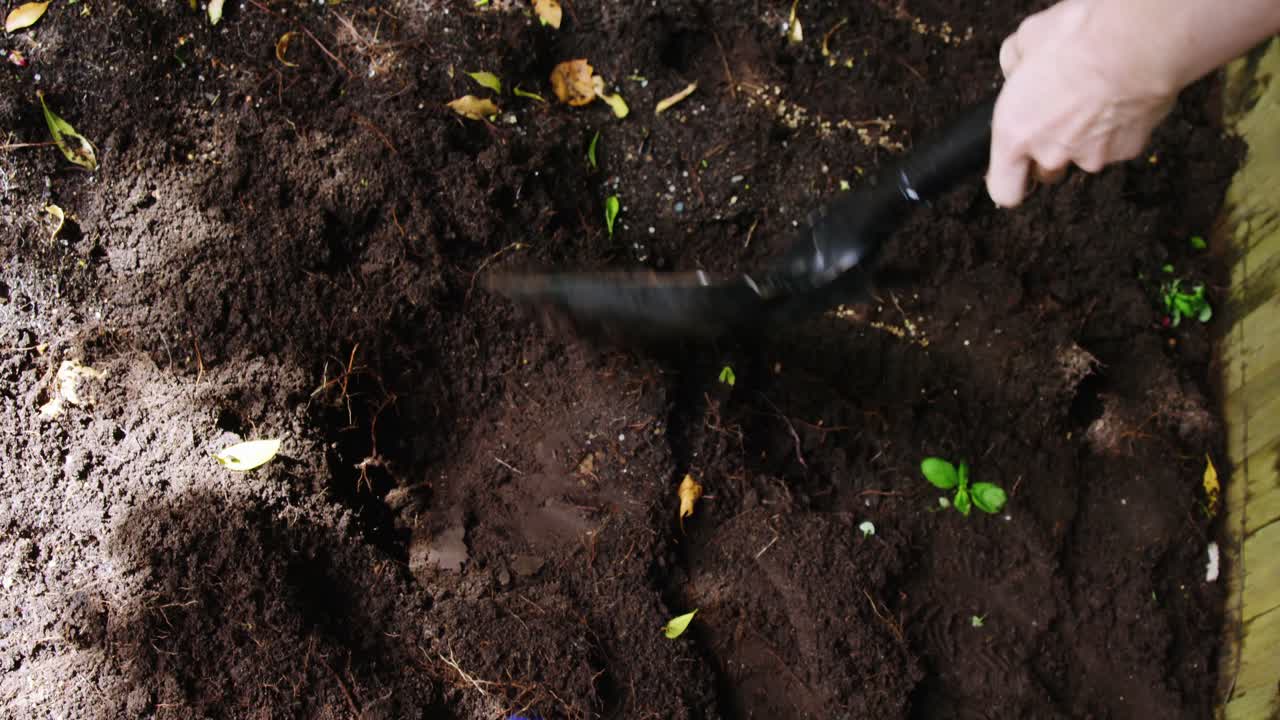 Persona che mescola il terreno con una pala in giardino