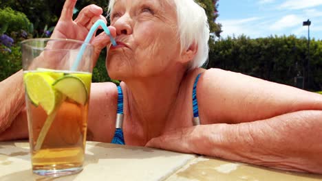 Mujer-Mayor-Tomando-Un-Vaso-De-Té-Helado-En-La-Piscina