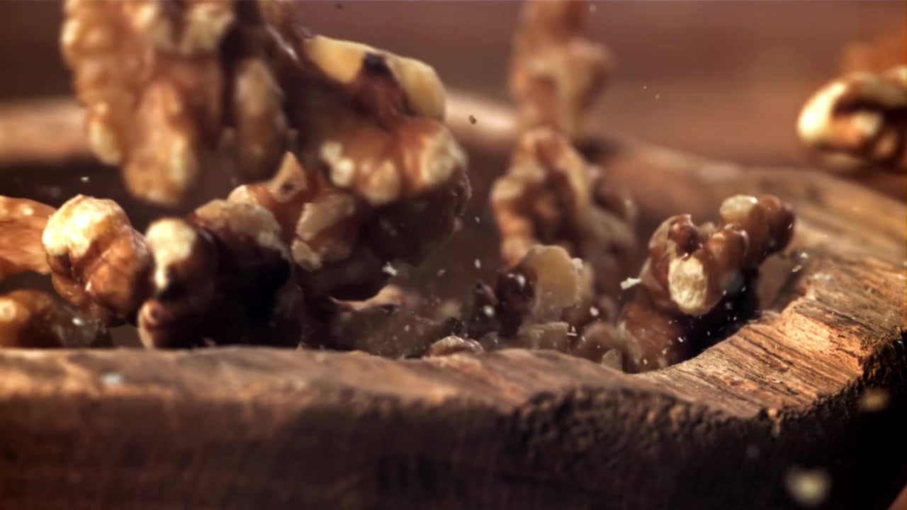 Noci Sgusciate che Cadono in una Ciotola di Legno Rustica al Rallentatore