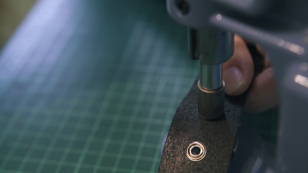 sastre fija los ojos en el cinturón de cuero con máquina de prensa