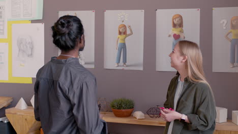 young female graphic designer explaining project to her colleague in an animation studio