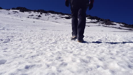 ángulo bajo: un excursionista solitario camina sobre la nieve hacia la lejana cresta de la cumbre de mtn