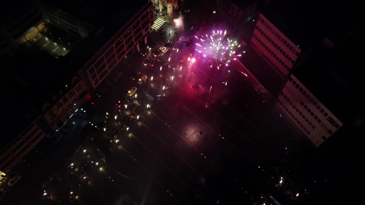 Drone che vola direttamente sopra fuochi d'artificio e folla che celebra il conto alla rovescia di Capodanno