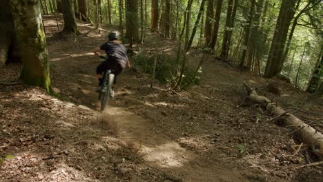 mountain biker lands from jump and rides through a dusty corner