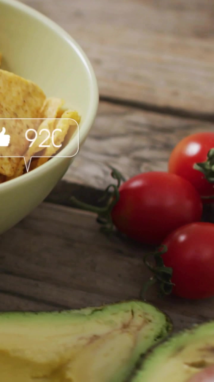 Panoramica della telecamera che mostra patatine, pomodoro, avocado mentre appaiono bolle social che aggiornano i conteggi per il marketing.