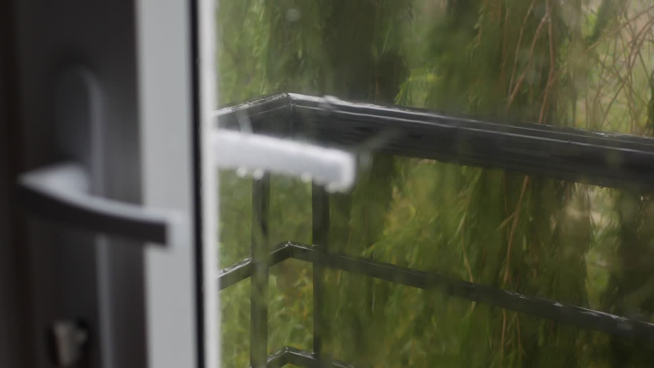 fuerte agua de lluvia se derrama contra el vidrio de la ventana y fluye hacia abajo. primer plano. gotas de lluvia en fondo de vidrio en la temporada de lluvias. 4k