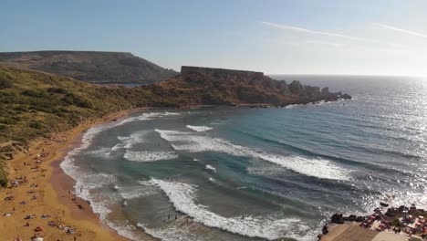 AERIAL:-Flying-backwards-above-beautiful-Ghajn-Tuffieha-Bay-in-summer,-Malta