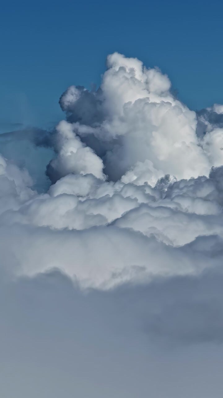 Cinematic drone footage capturing large cumulus clouds drifting across a bright blue sky, showcasing natural atmospheric beauty and serene weather conditions.