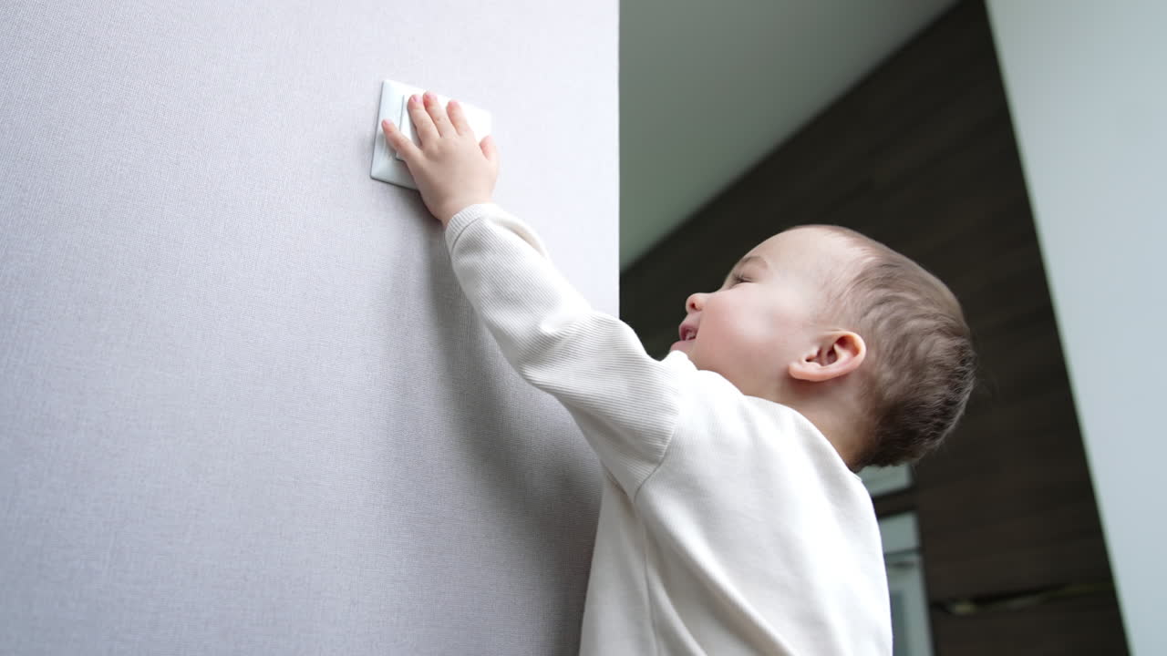Sweet smiling little toddler and his daddy playing with light. Father and son take turns in switching the light on and off. Low angle view.
