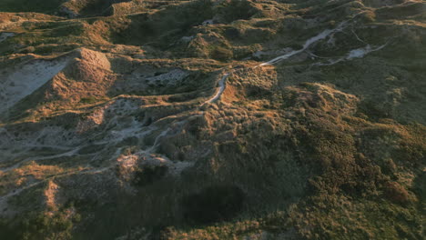 Sunset-trails-on-Denmark's-dune-landscape,-casting-long-shadows