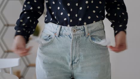 portrait of a frustrated unemployed woman in a shirt, turning out empty pockets, showing the lack of money