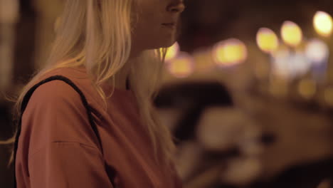 woman applying lipgloss outside at night