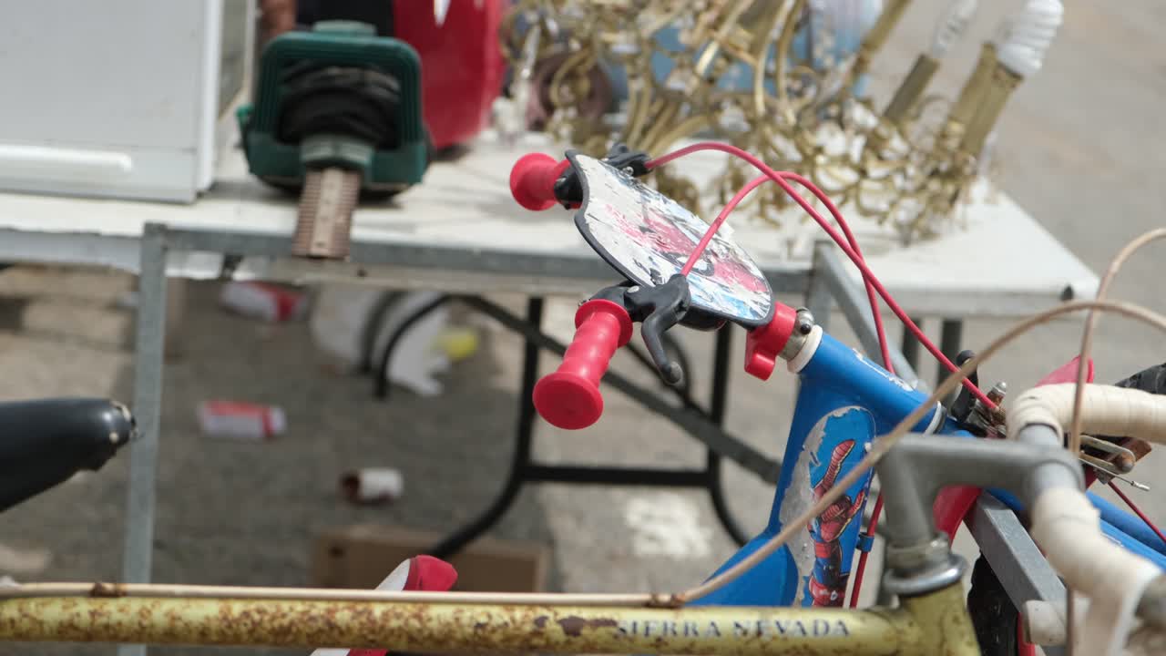 A vintage, gold-colored metallic chandelier, along with other antique items, is elegantly displayed at the flea market, attracting attention with its timeless charm and character.