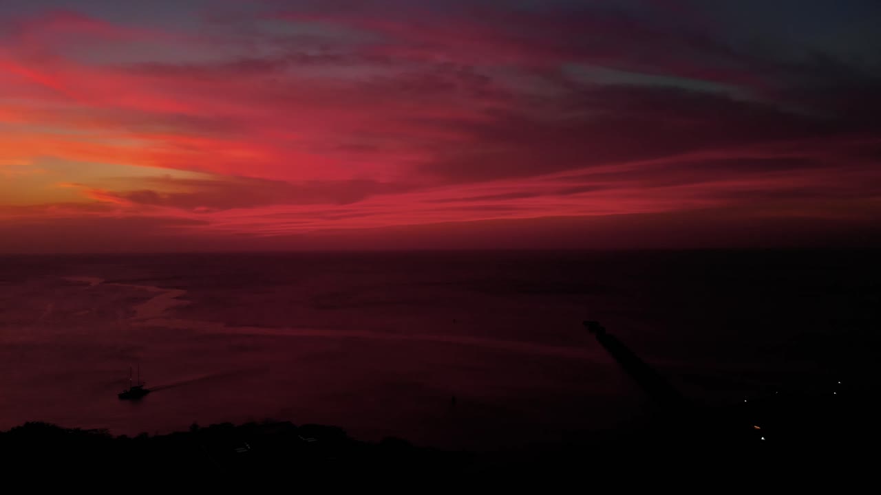 Atemberaubende Drohnenaufnahme eines karibischen Sonnenuntergangs mit einer Yacht im Vordergrund.