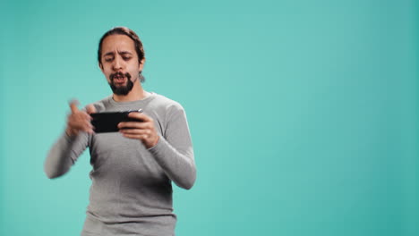 man playing videogames on smartphone, celebrating after being victorious