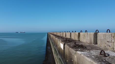 Kranschuss-Entlang-Eines-Hafens,-Hafenmauer,-Blick-Auf-Ein-Schiff-Und-Den-Kai