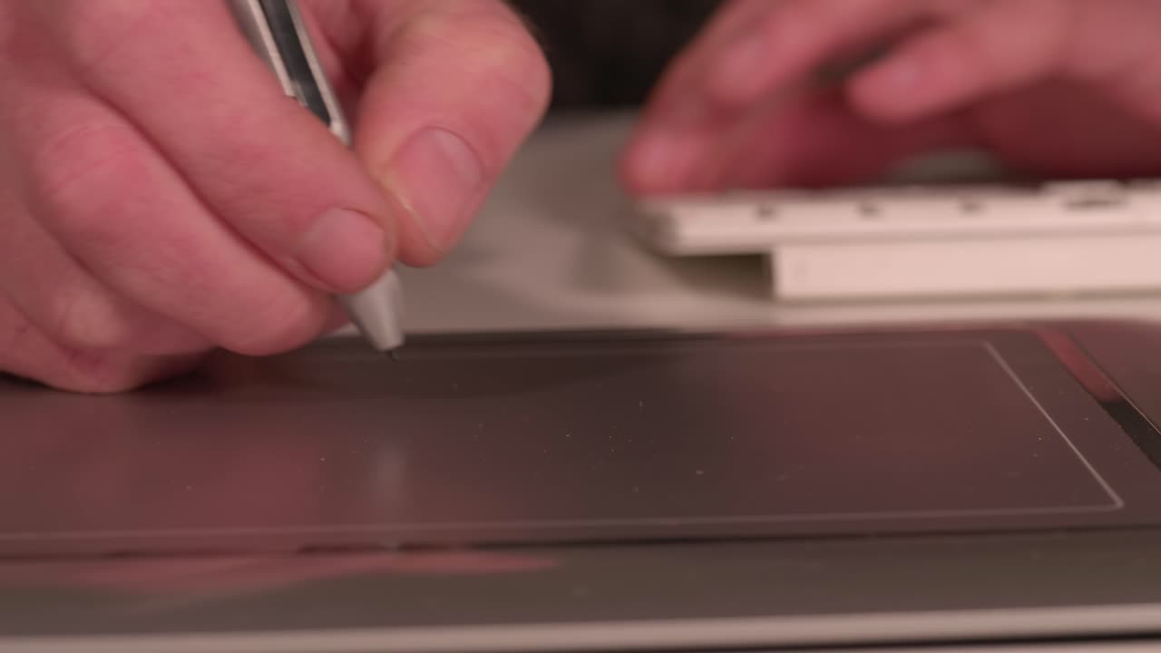 Close up on hands using a keyboard and track pad to do work, static