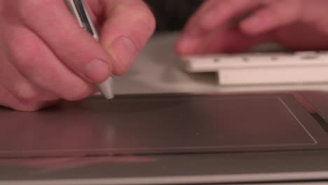 close up on hands using a keyboard and track pad to do work, static