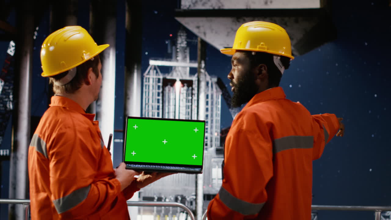 Green screen next to oil rig technicians analyze fuel extraction on platform