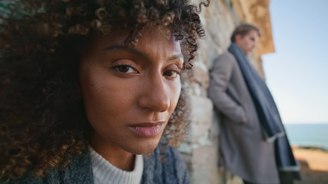 Curly brunette looking camera at abandoned place portrait. Diverse pair posing