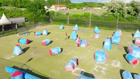 personas jugando al paintball en un campo al aire libre con bunkers inflables en austria
