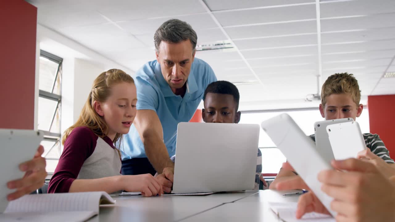 Teacher assisting schoolkids on laptop 4k