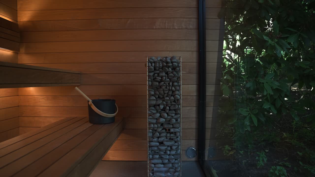 empujar lentamente dentro de una luxuosa sauna de madera de cedro completa con calor de roca alta, bancos de dos niveles y ventana de piso a techo que muestra la vista hacia el área boscosa