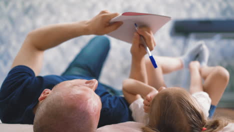 bald father and little daughter lie