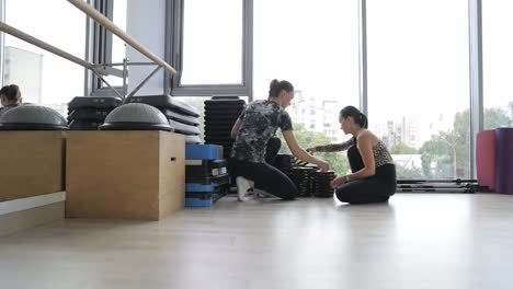 woman receiving pilates instruction with equipment
