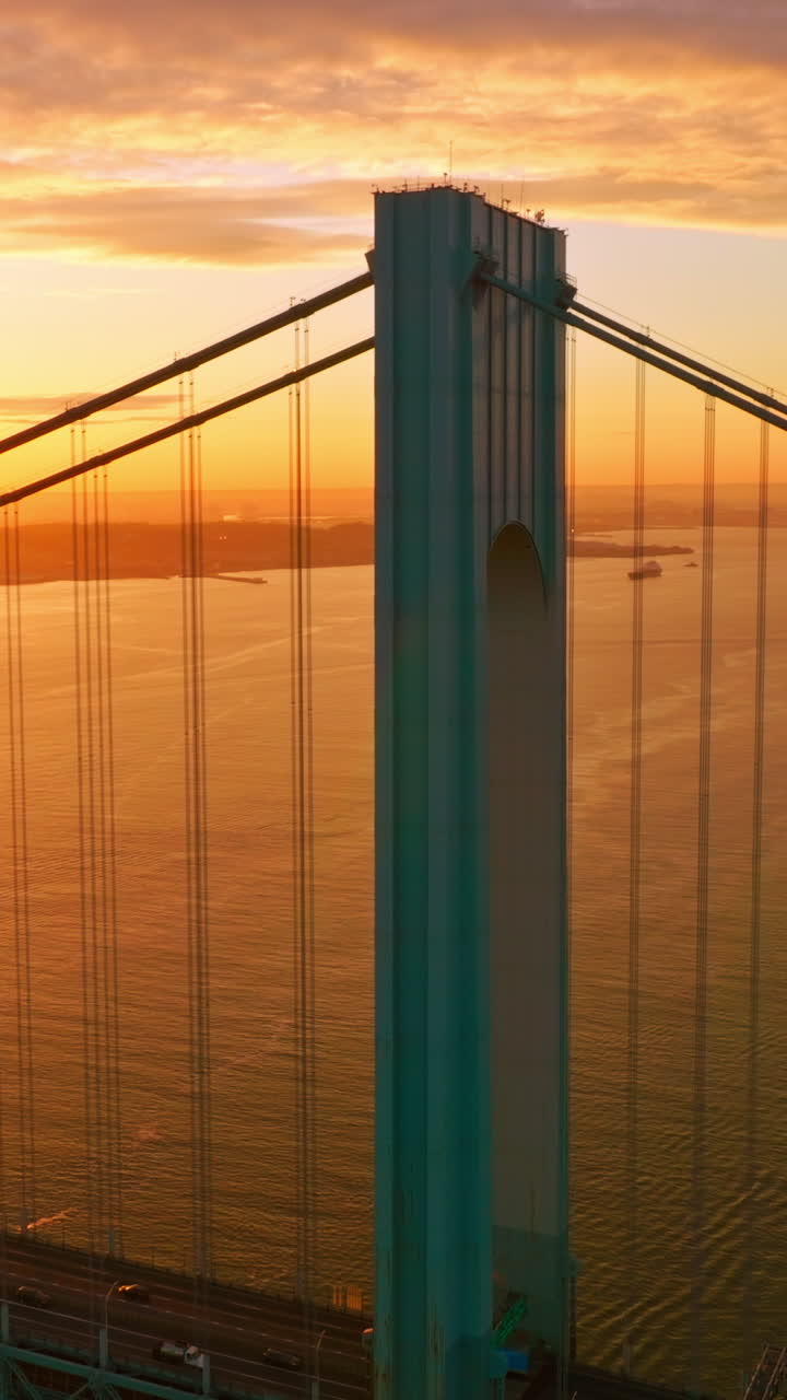 Blue massive supports of Whitestone bridge in the orange light. Beautiful picture of sunset over East River. Vertical video