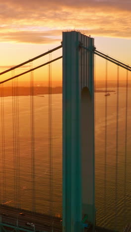 blue massive supports of whitestone bridge in the orange light. beautiful picture of sunset over east river. vertical video