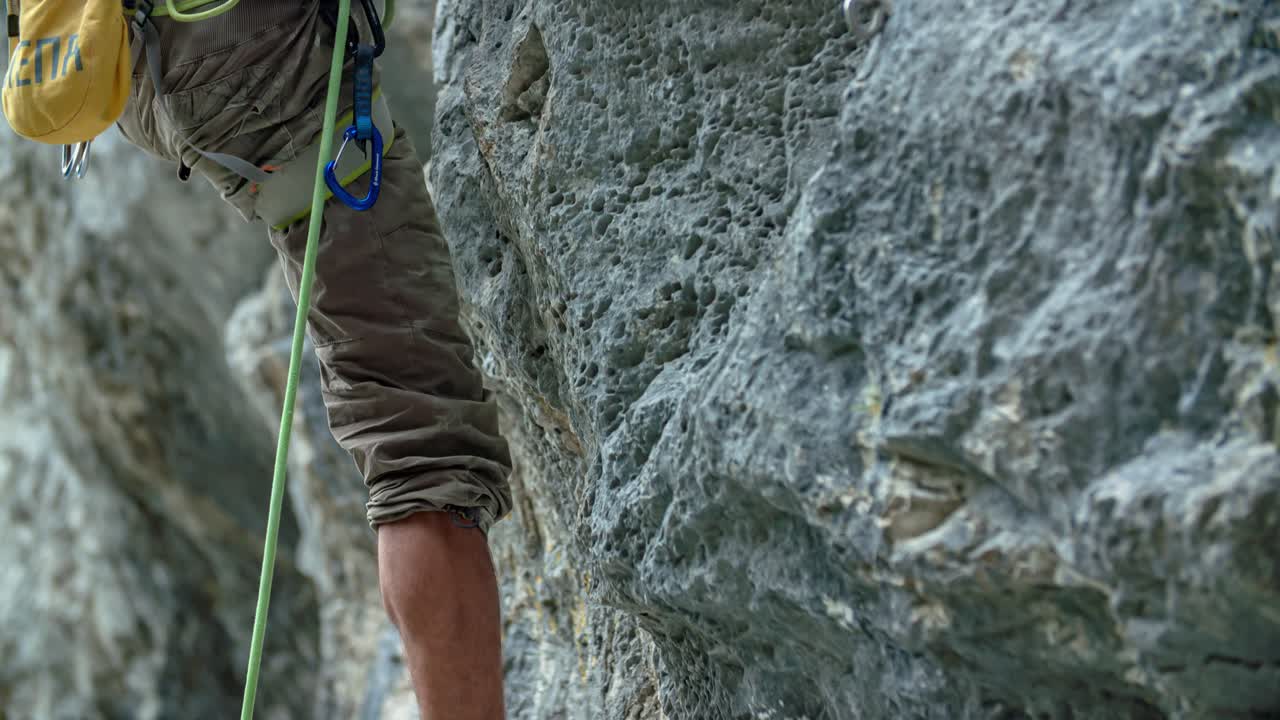 rock climber. Close up lower half body. Vertical rock wall. tilt up