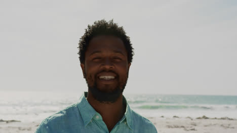 Young-man-standing-on-beach-in-the-sunshine-4k